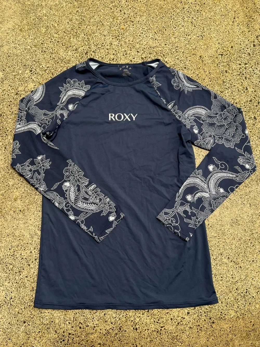 Roxy rashguard in blue with white floral design at sleeves